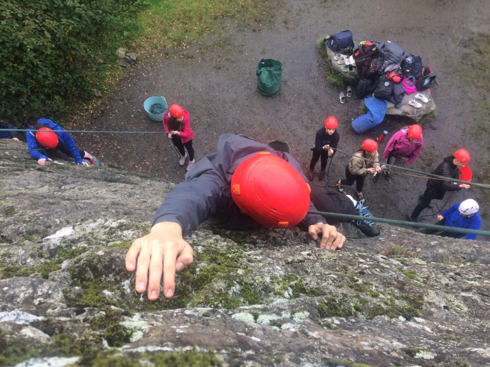 climber reaching top of cliff from above
